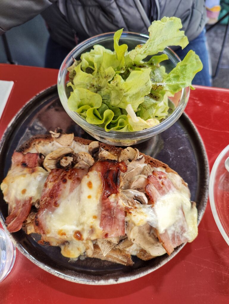 Open face sandwich or tartine at Le Tuyau in Aix. Topped with Serrano ham and melted cheese. Side of green salad.