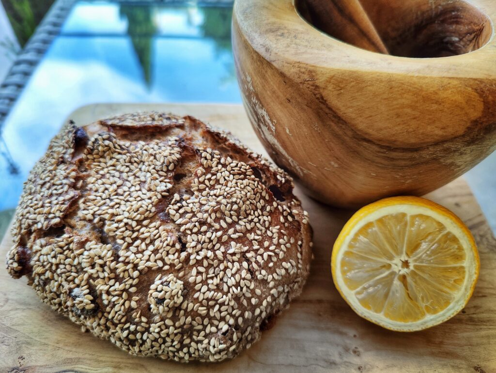 Loaf of bread, next to a lemon and a wooden mortar and pestle