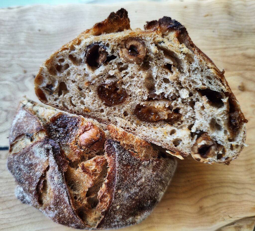 A cross-section of a loaf of bread filled with apricot and hazelnuts.