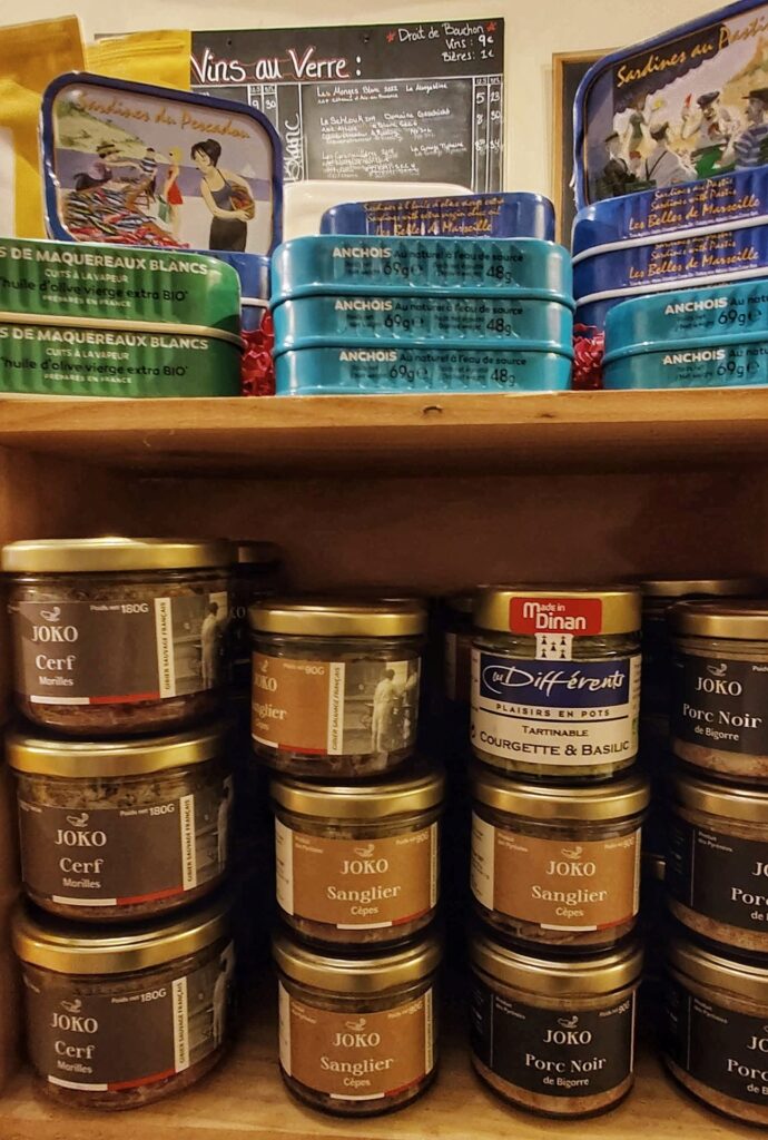 Sardine cans on a top shelf and pate jars on shelf beneath